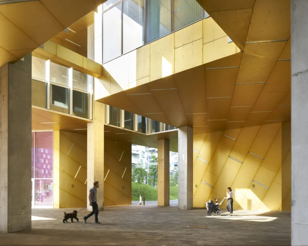 Golden yellow-clad covered public space at the base of the 8 House by BIG in Copenhagen