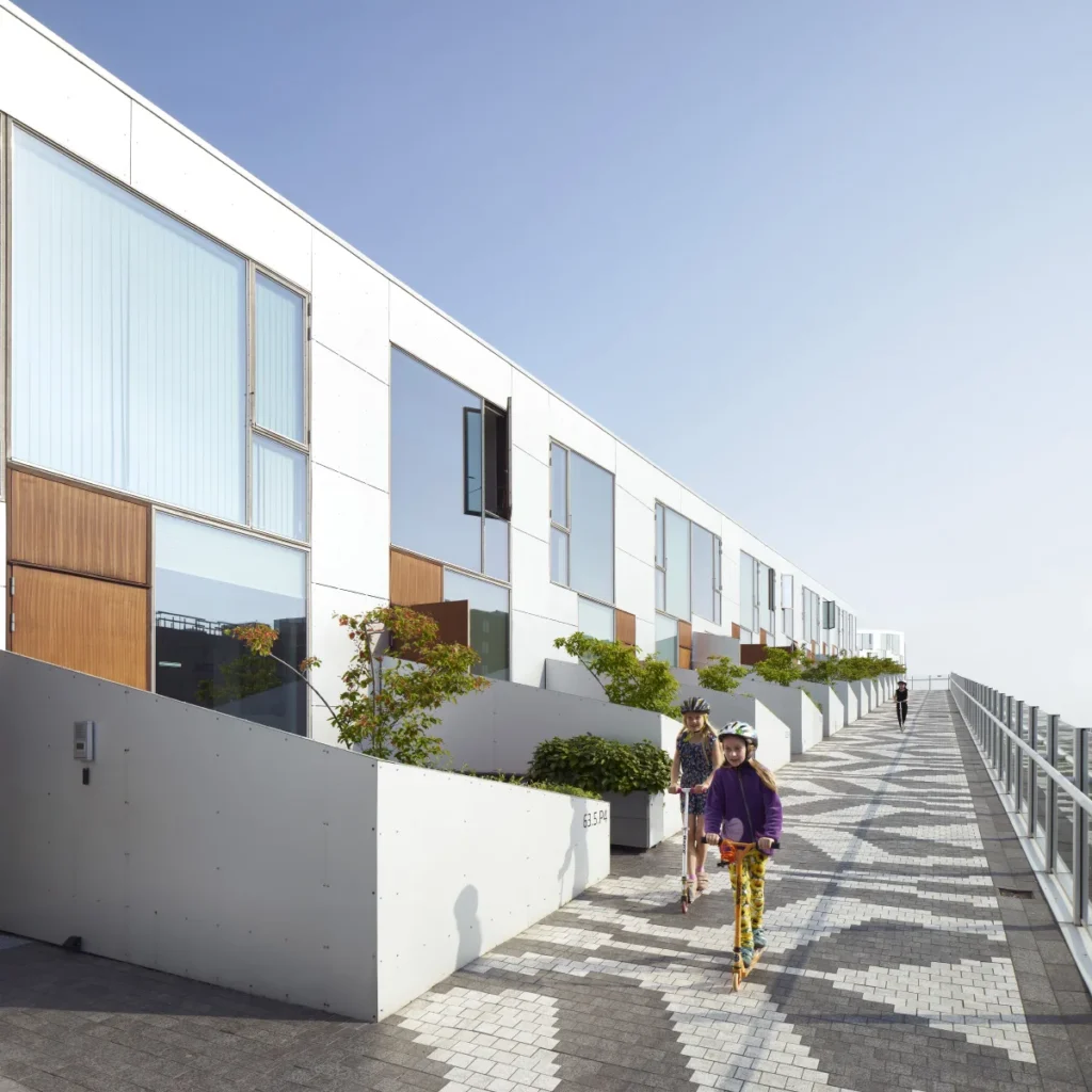 Friends riding scooters on the promenade path of the 8 House in Ørestad, Copenhagen