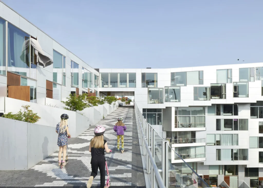 Friends riding scooters on the promenade path of the 8 House in Ørestad, Copenhagen by BIG / Bjarke Ingels Grpoup