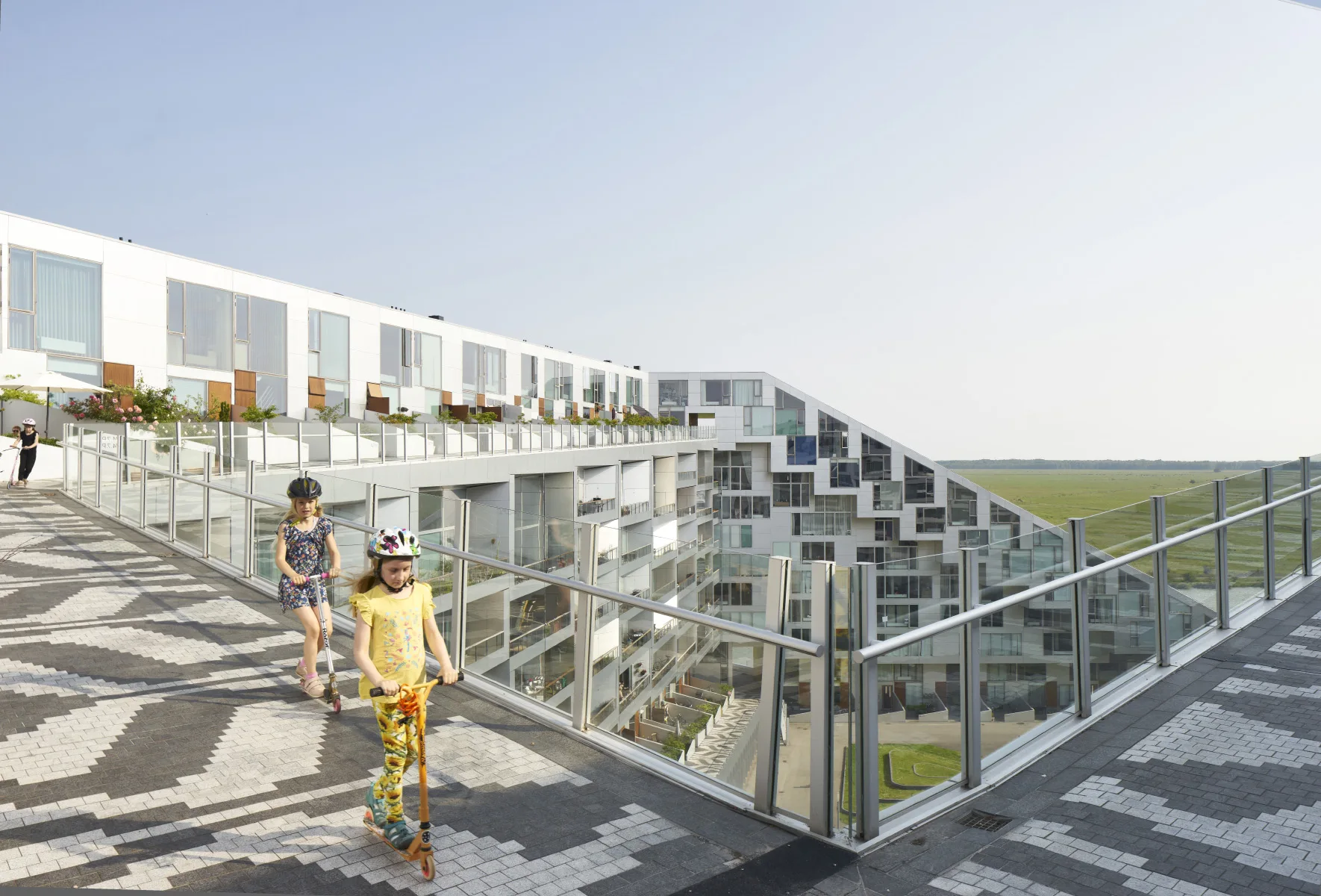 Kids riding scooters on the promenade path of the 8 House in Ørestad, Copenhagen by BIG / Bjarke Ingels Grpoup