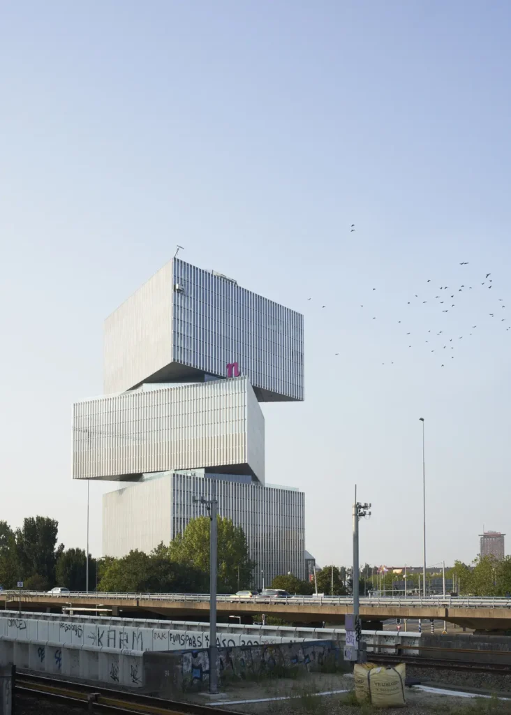 Birds circling the nHow Amsterdam RAI Hotel by OMA seen from railway platform at RAI station