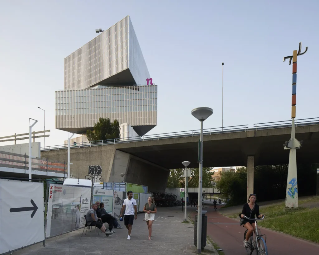 Evening view of nHow hotel with city lights and traffic in Zuidas Amsterdam