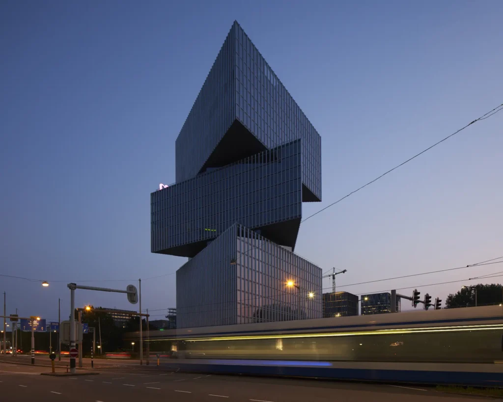 Three cantilevered volumes of nHow Amsterdam RAI Hotel by OMA seen from street level at night