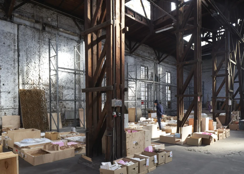 Person reviewing architectural models on tables in Berlin warehouse for Barkow Leibinger show