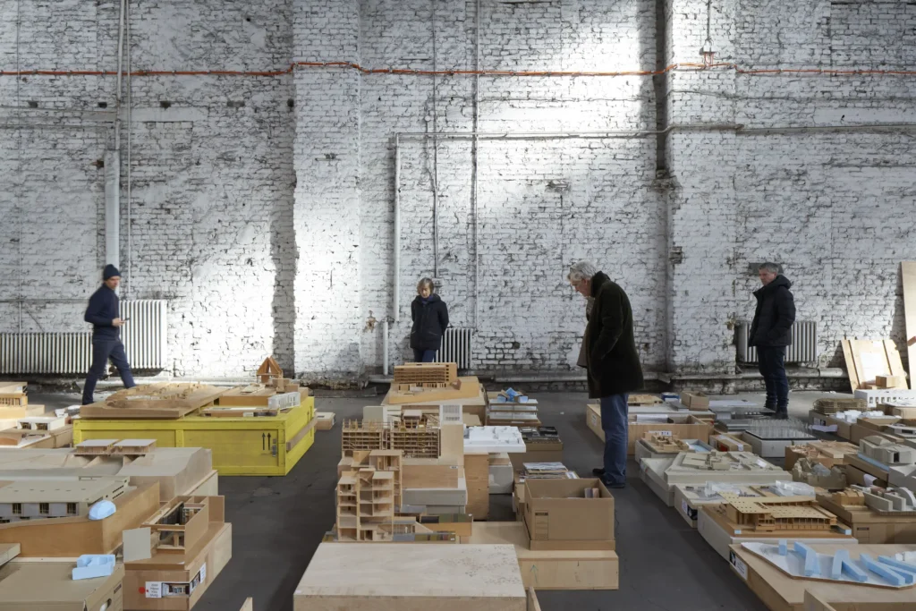 Frank Barkow reviewing architectural models on tables in Berlin warehouse for Barkow Leibinger show