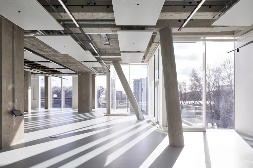 Exposed diagonal concrete columns casting shadows on empty floor at UP! Berlin