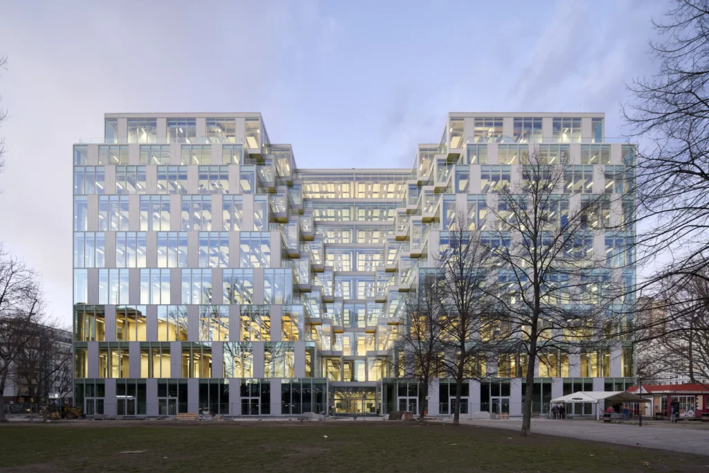 Evening view of UP! Berlin with illuminated glass facade by Jasper Architects and Gewers Pudewill