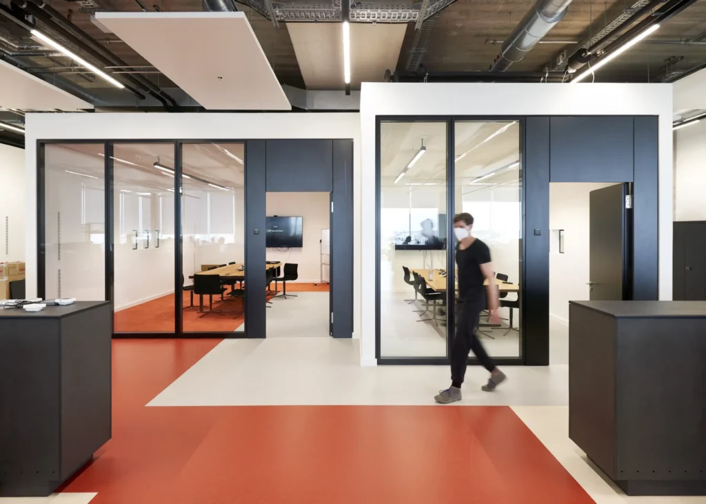 Meeting rooms with red floor and exposed ceiling at UP! Berlin office floor