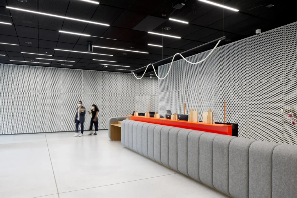 Two people walking in reception area with grey and orange fabric front desk UP! Berlin