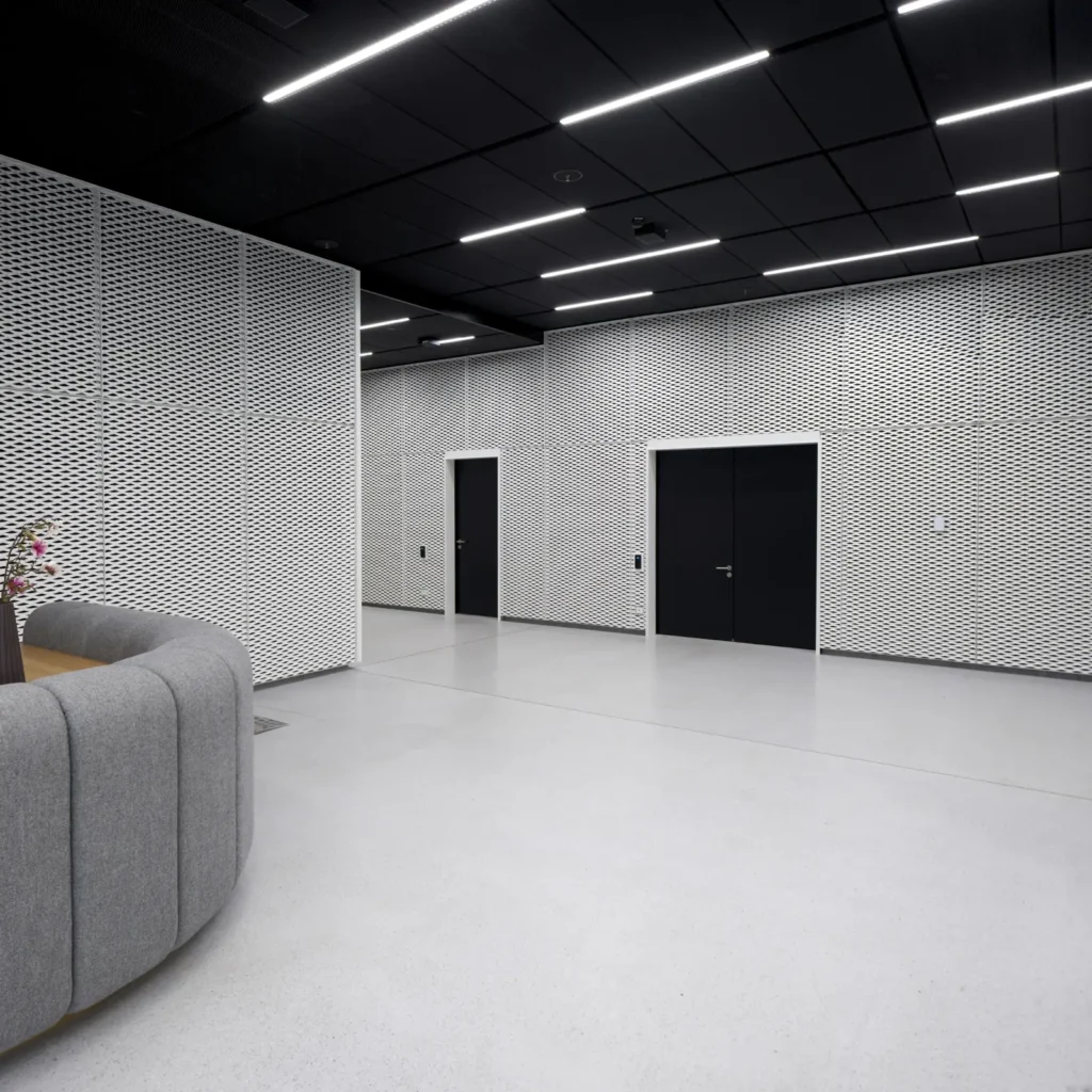 Lobby with white perforated metal walls and dark ceiling at UP! Berlin by Jasper Architects