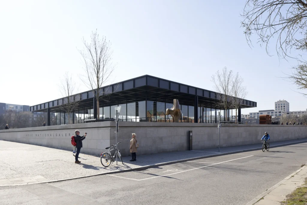 Pedestrians in front of the corner view of the Neue Nationalgalerie showing the cantilevered steel roof in Berlin