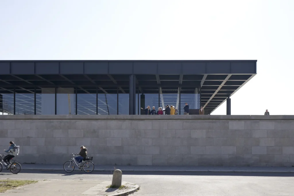 Granite podium wall of the Neue Nationalgalerie seen from street level with cyclists in Berlin