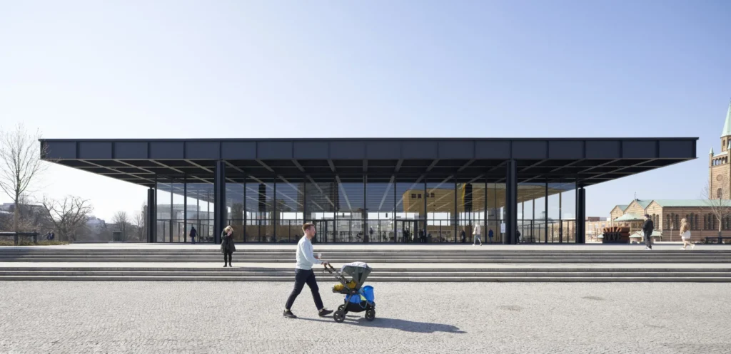Father with stroller in front of Neue Nationalgalerie with St. Matthäus-Kirche visible in the Kulturforum Berlin