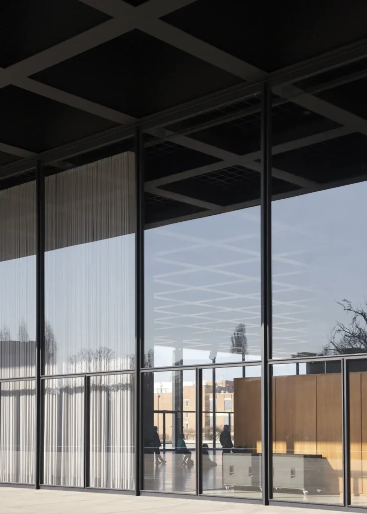 Glass facade of the Neue Nationalgalerie with exhibition curtains visible inside Glass corner detail