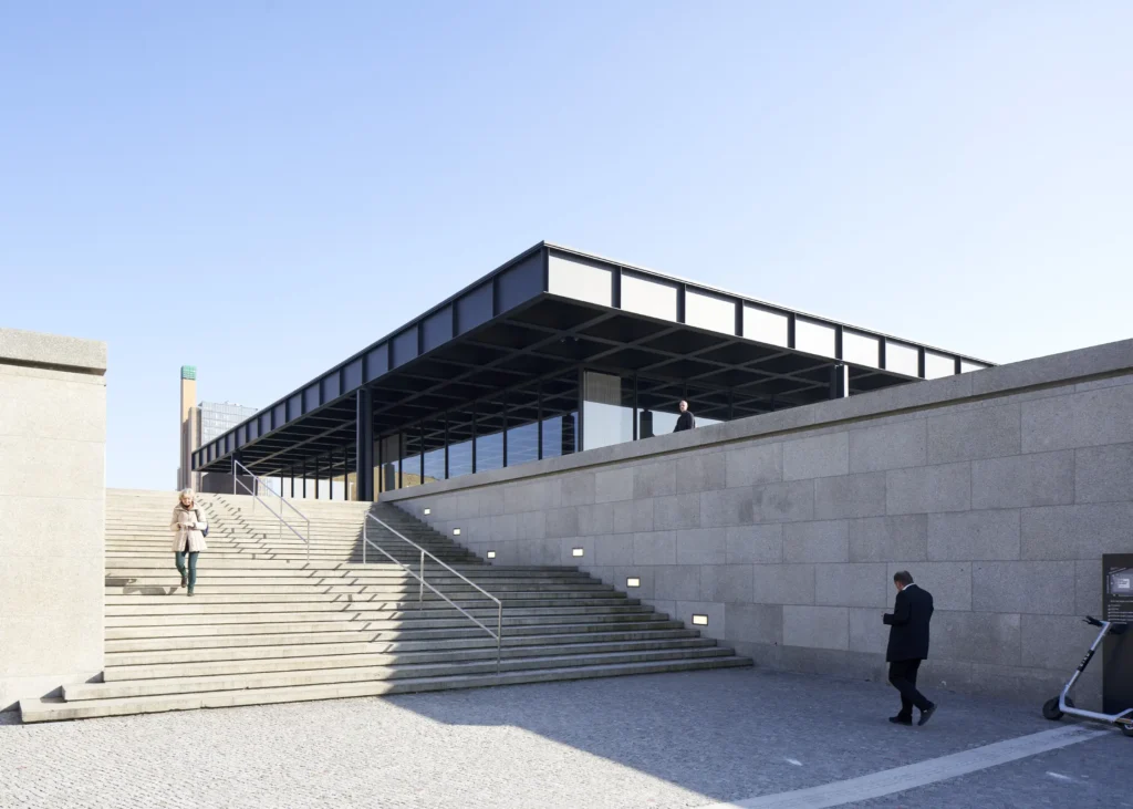Granite podium stairs of the Neue Nationalgalerie with Berlin in the background and pedestrians