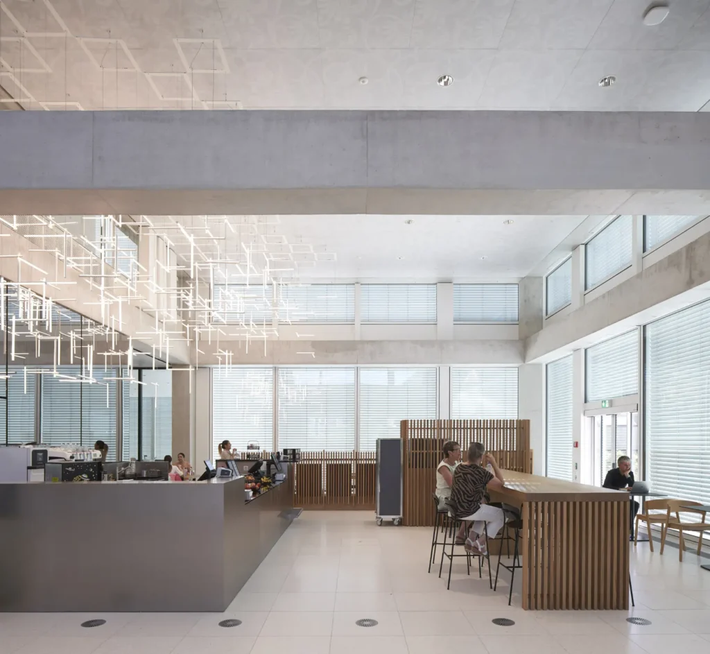 People in the cafe area with light installation on the ceiling of the SQUARE Learning Center in St. Gallen