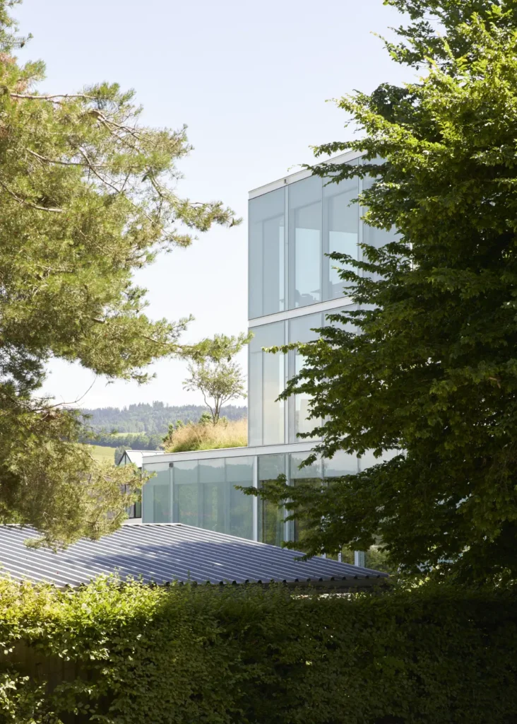 Glass facade of the SQUARE Learning Center framed by trees on the campus in St. Gallen
