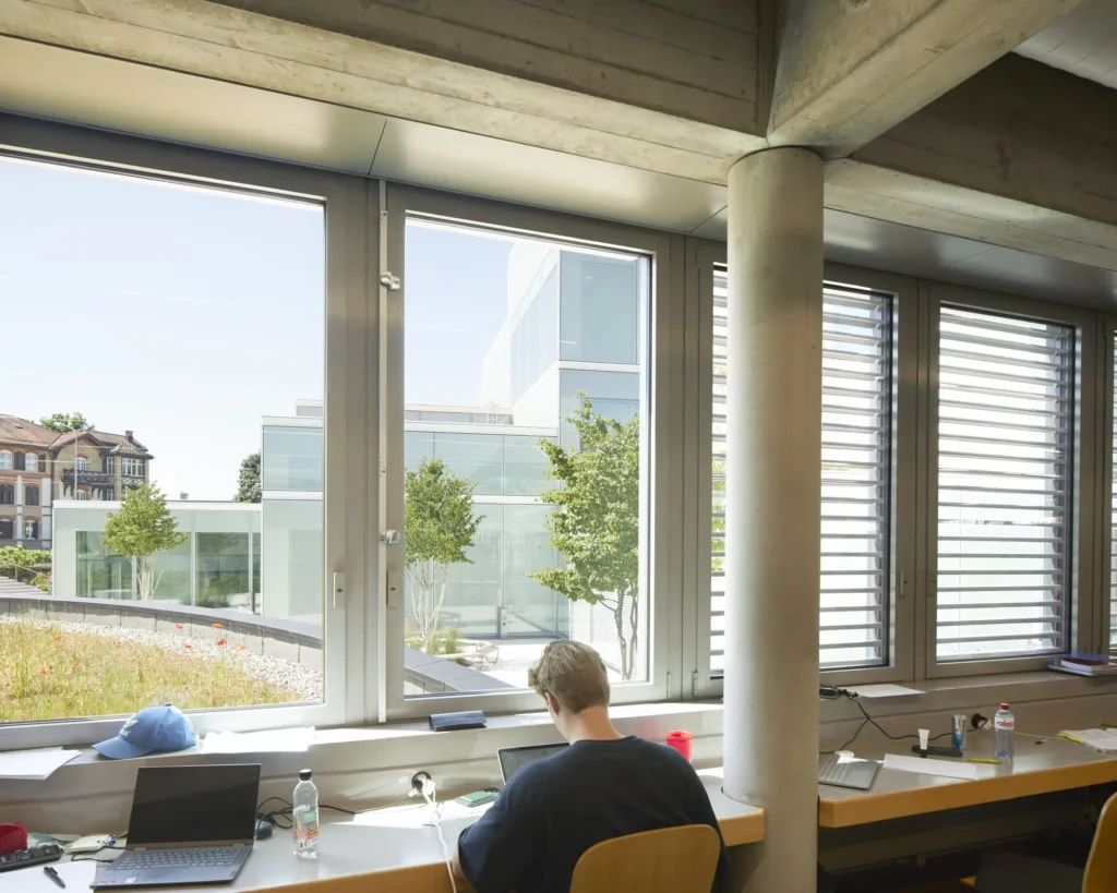 Student working at a window desk with views over the St. Gallen hills