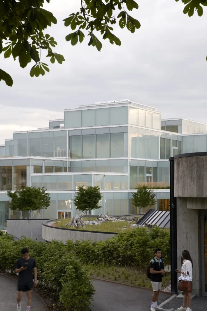 Stacked glass modules of the SQUARE Learning Center by Sou Fujimoto in St. Gallen framed by trees