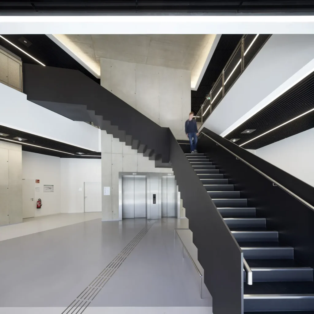 Black staircase with student and linear lighting at the KMAC building by studioMDA