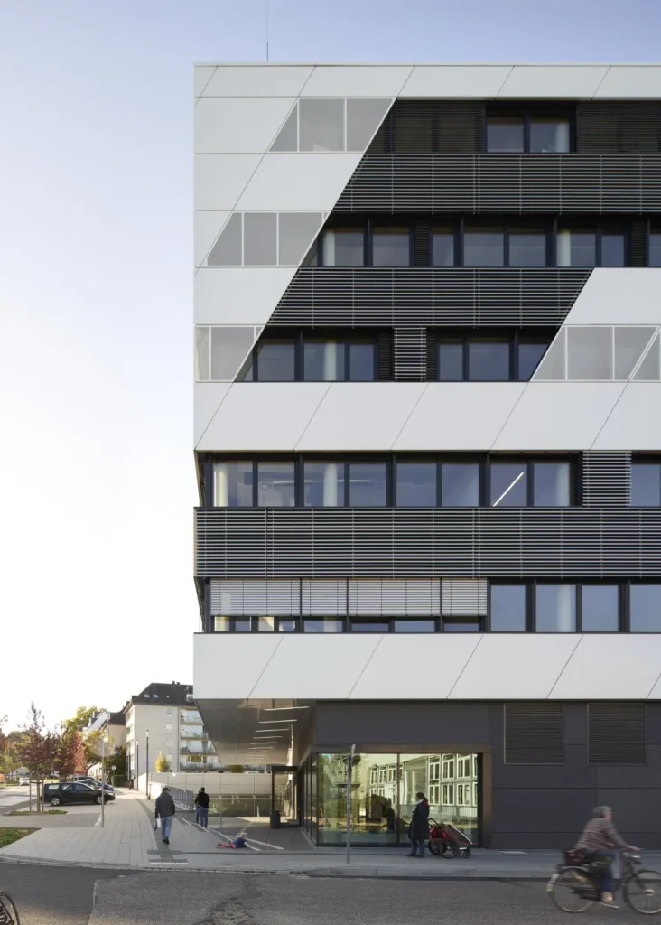 Cyclist passing the entrance to the KMAC building by studioMDA in Aachen with pedestrians