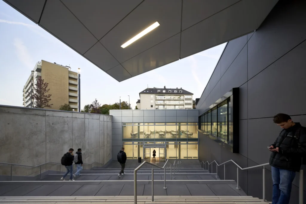 Illuminated entry and students walking down stairs to the lecture hall of the KMAC in Aachen