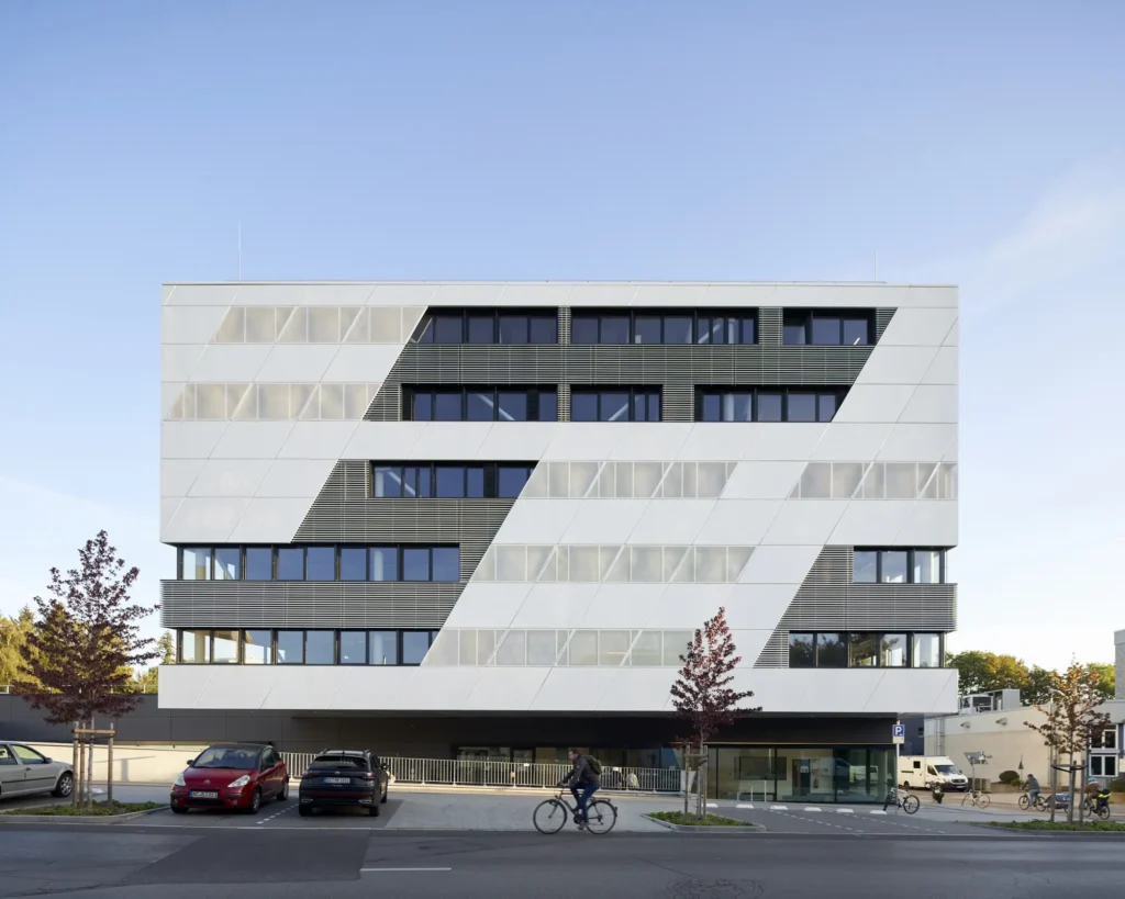 Man cycling in front of abstract facade with angled window strips at the KMAC by studioMDA