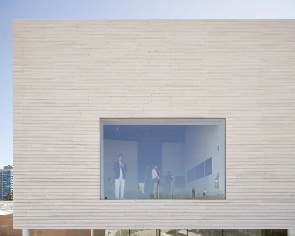 Visitor viewing exhibition through large window with harbour view at Sydney Modern