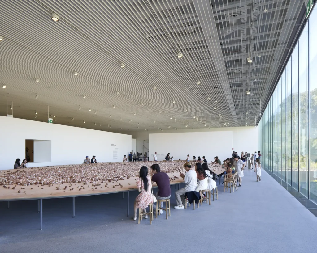 Large gallery space with floor installation and visitors seated at tables at Art Gallery of New South Wales