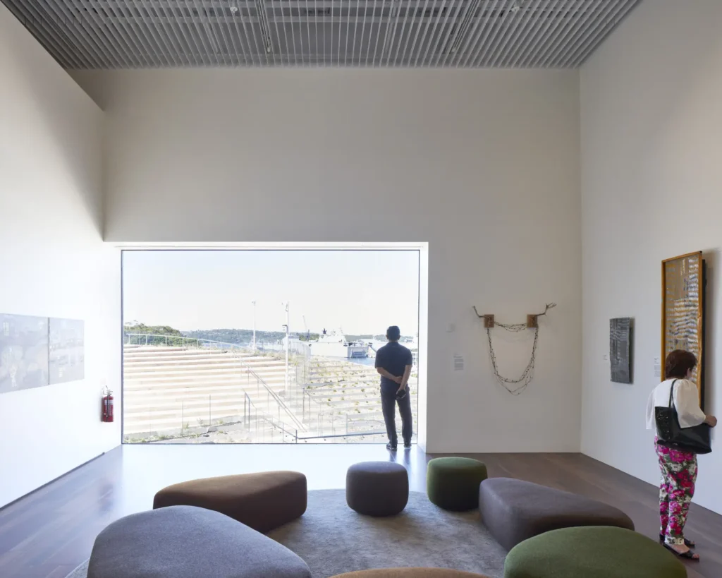 Visitor overlooking the harbour through large window with harbour view at Sydney Modern