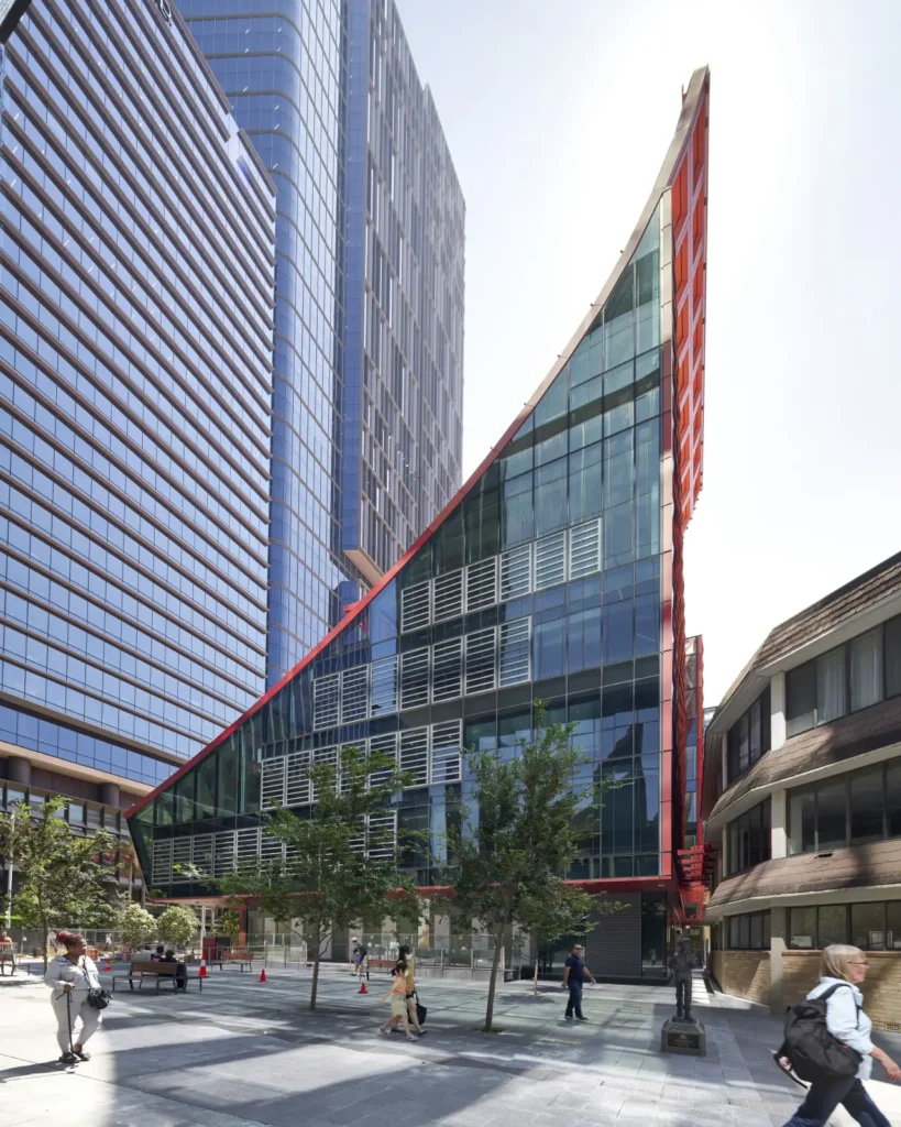 Pedestrians crossing in front of the iconic red roof of PHIVE Community Center by Manuelle Gautrand