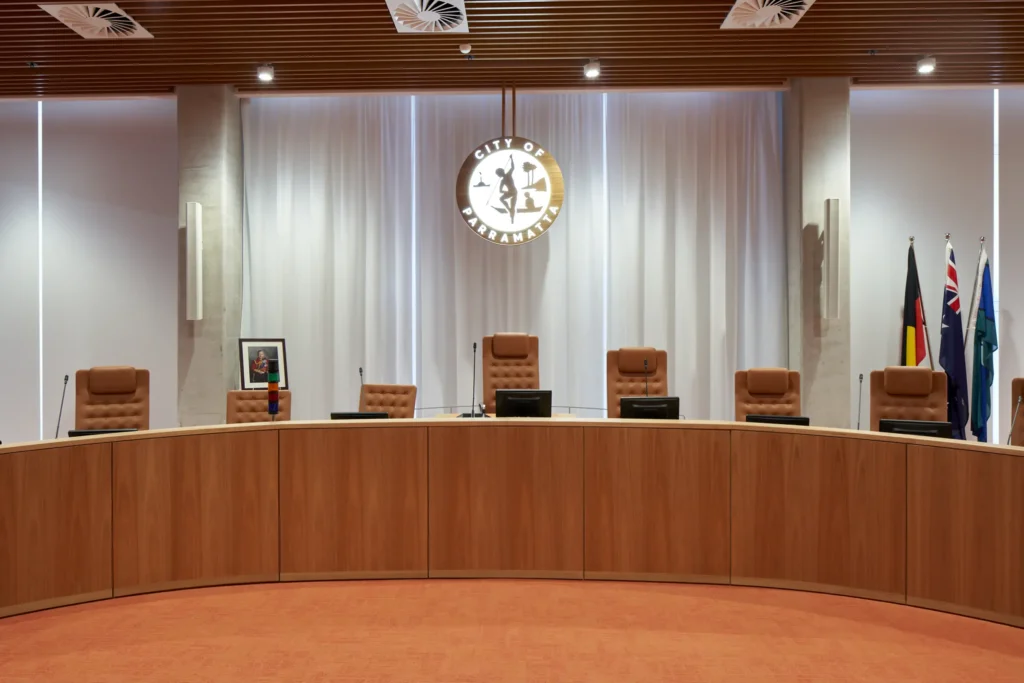 Parramatta Council meeting room with timber-clad curved bench and flags inside PHIVE