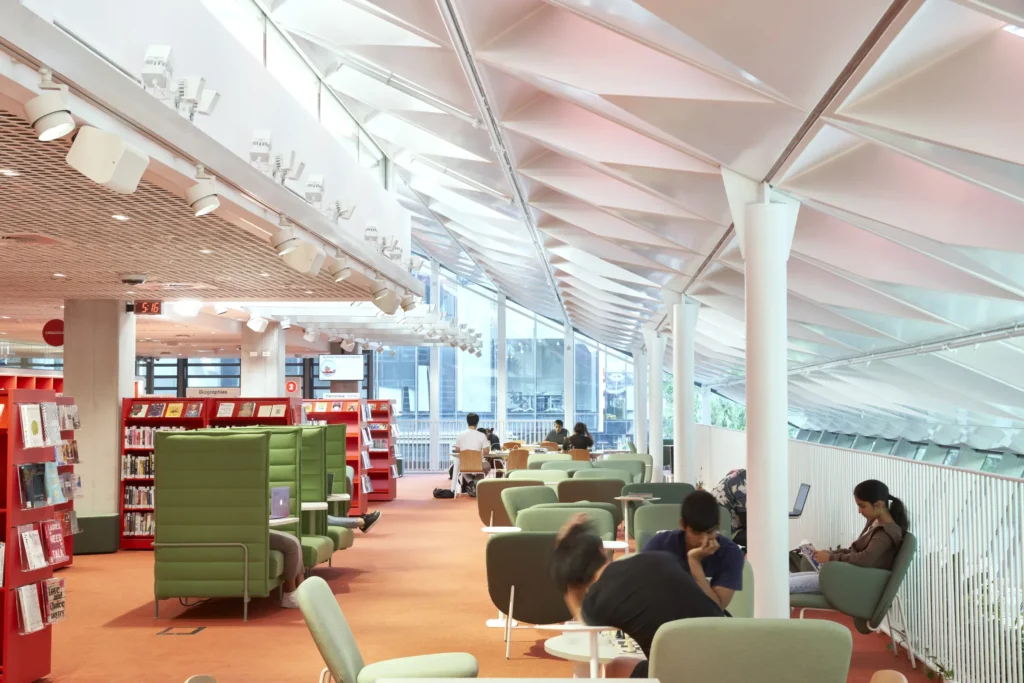 Public library reading area with orange carpet and colourful bookshelves inside PHIVE Parramatta