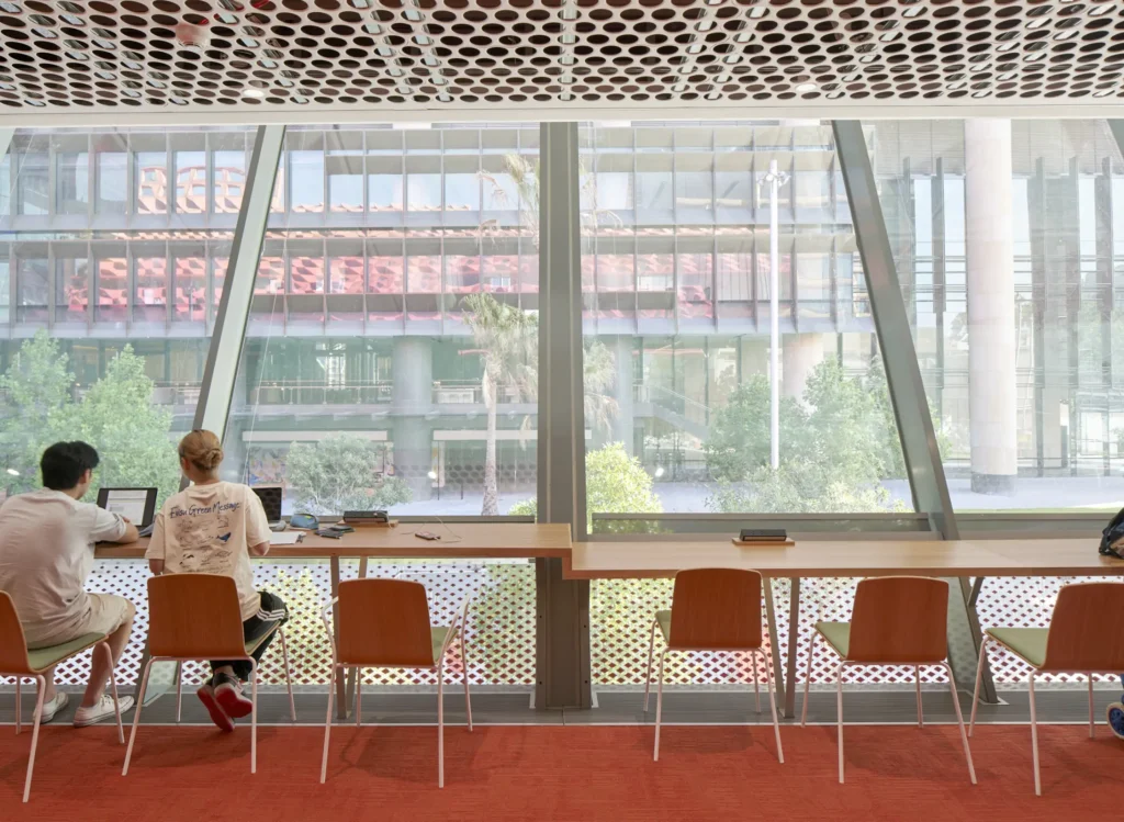 Bookshelves and seating on red carpet under angular white ceiling at PHIVE by Manuelle Gautrand