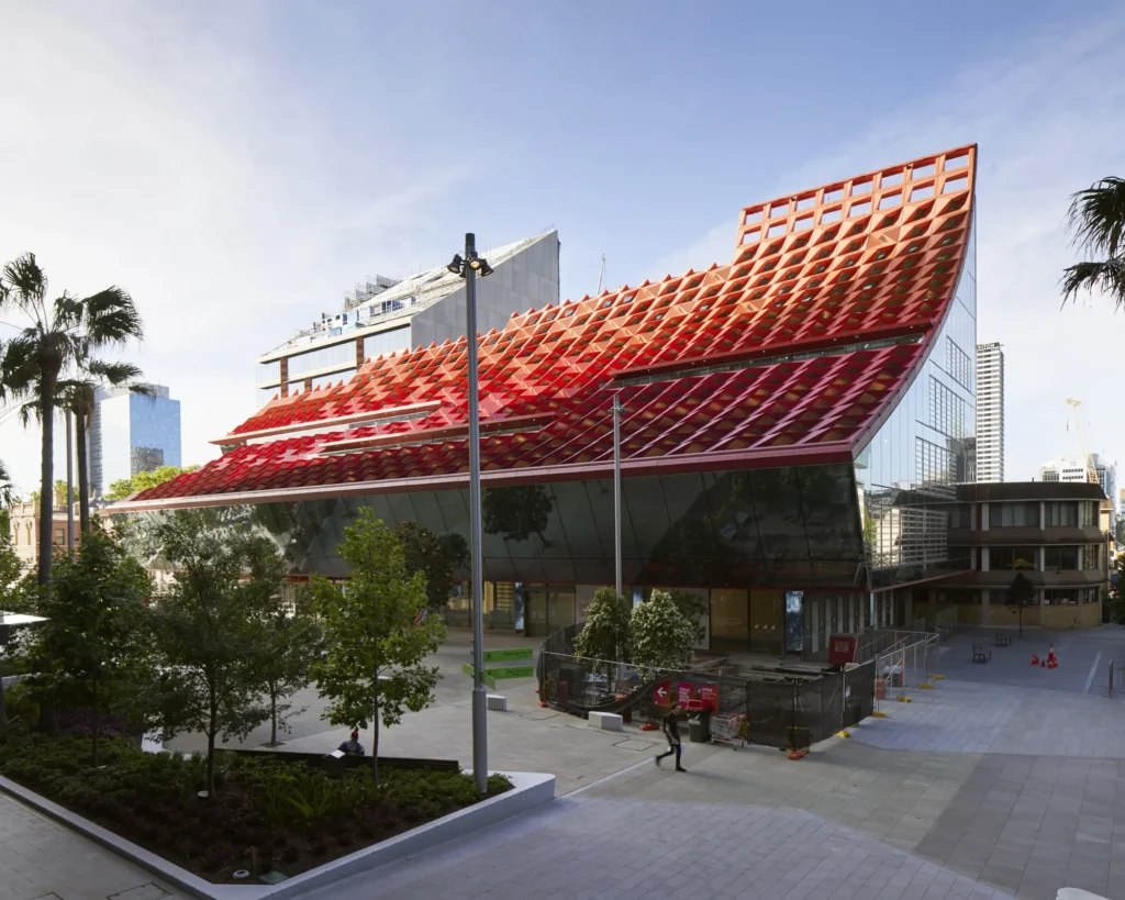 Pedestrians crossing in front of the iconic red roof of PHIVE Community Center by Manuelle Gautrand