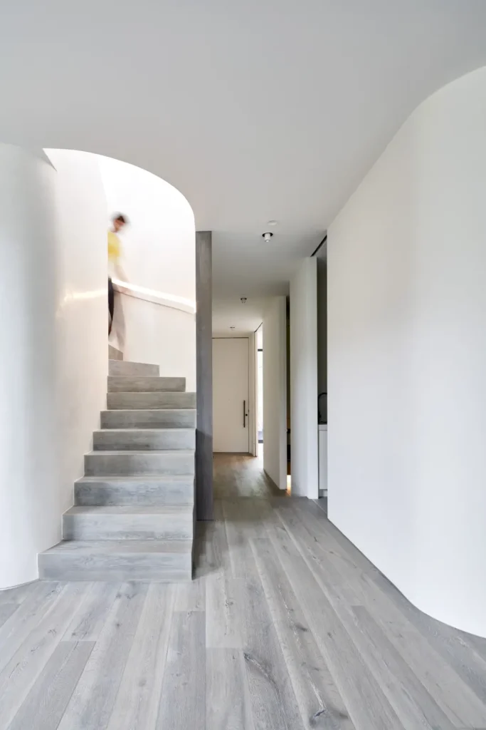 Person descending the dark ash staircase in light-filled hallway at Alexandra Street South Yarra