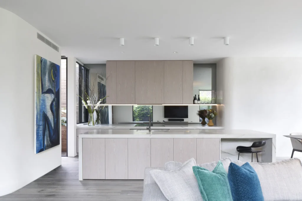 Kitchen and living area with white stone countertops and timber cabinetry at Alexandra Street Melbourne