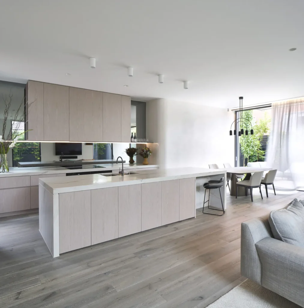 pen-plan kitchen with stone island bench and billowing curtains at Alexandra Street by Megowan Architectural