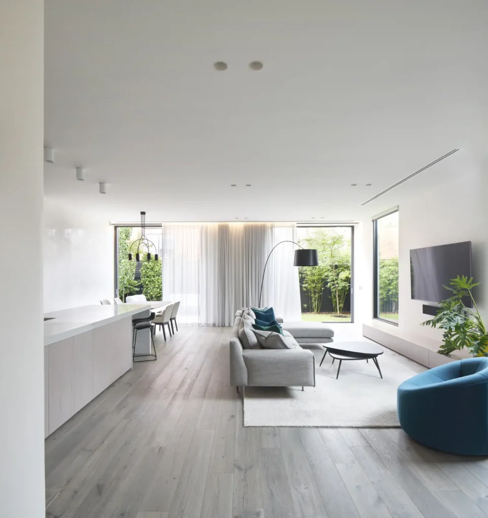 Living space with teal cushions and full-height glazing at Alexandra Street residence South Yarra
