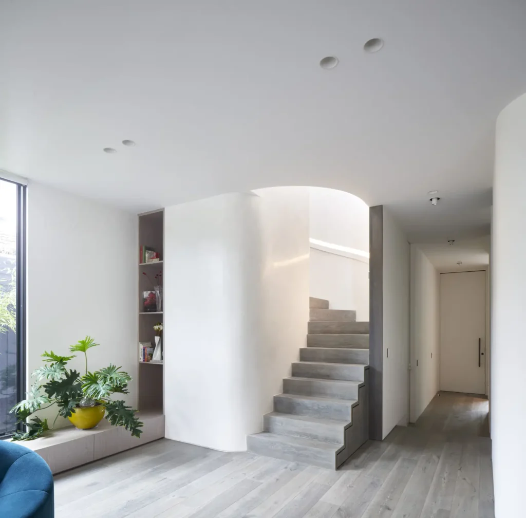 Curved white stairwell with dark ash wooden steps and recessed lighting at Alexandra Street residence