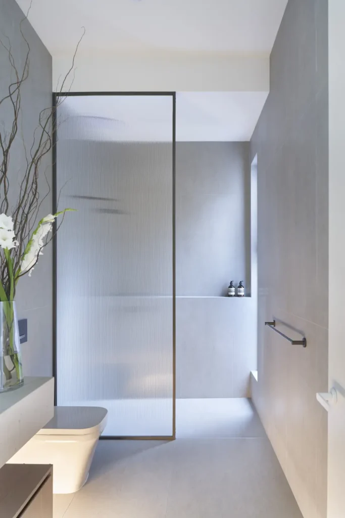 Shower with fluted glass screen and matte black fixtures at Alexandra Street residence