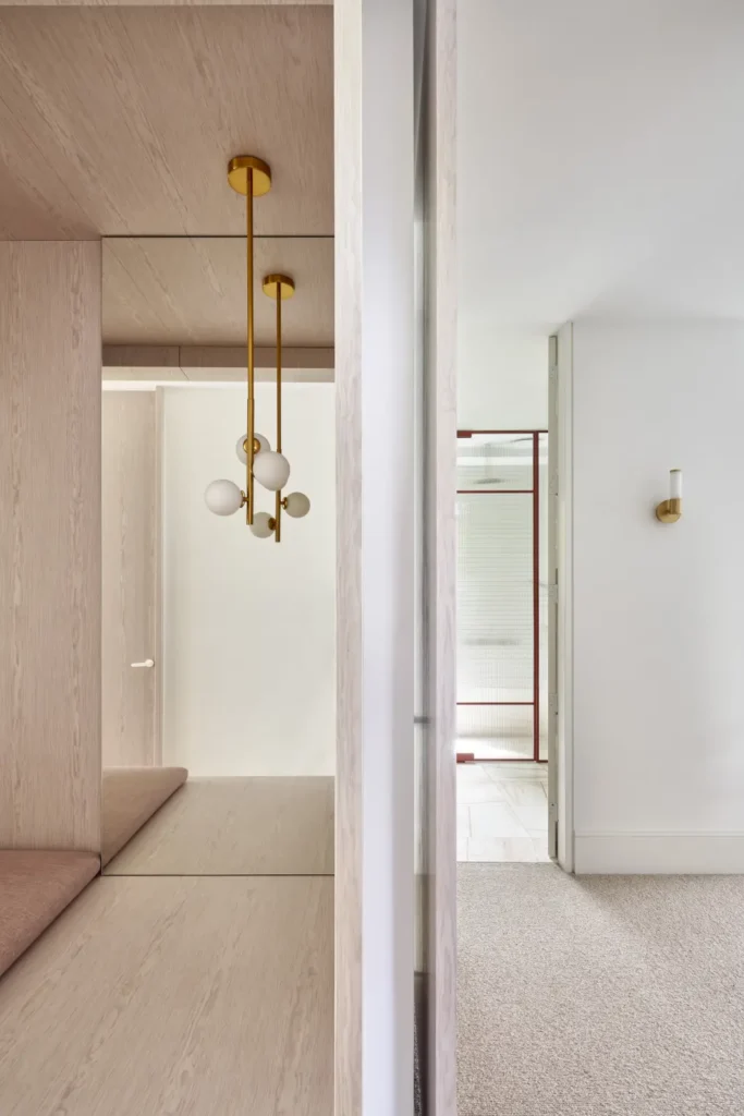 Hallway with timber-clad joinery and person walking through Lindsay house by Megowan Architectural