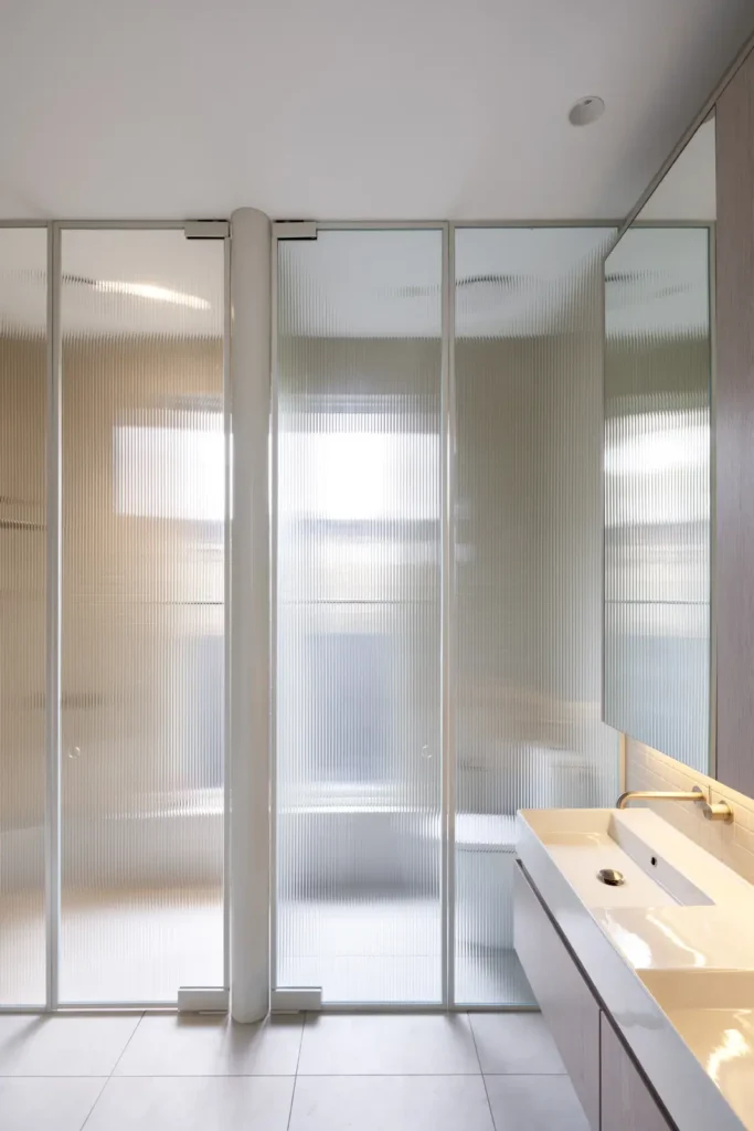 Shower area with translucent glass and red steel framing at Lindsay by Megowan Architectural