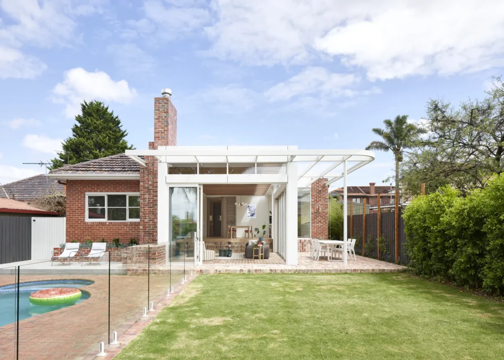 Garden elevation of Lindsay renovation showing new addition with exposed steel frame and glazing