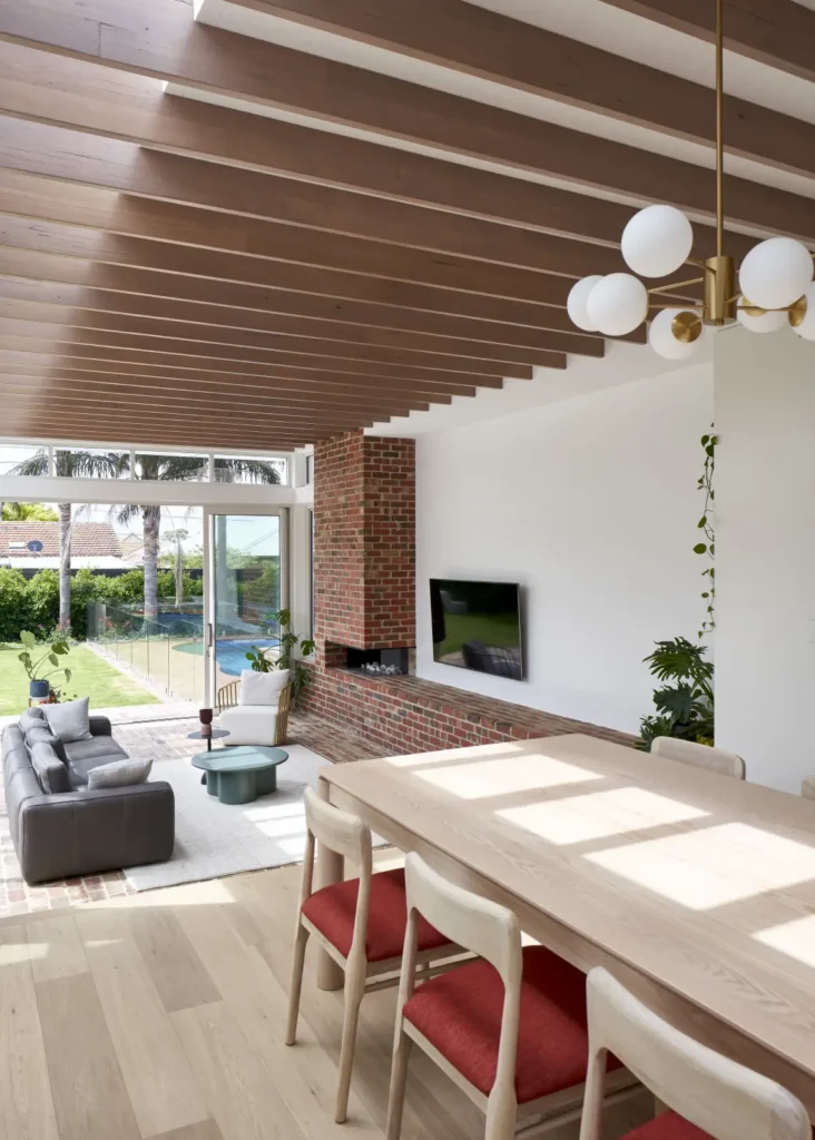 Dining area with red accent chairs beneath hardwood rafter ceiling at Lindsay by Megowan Architectural