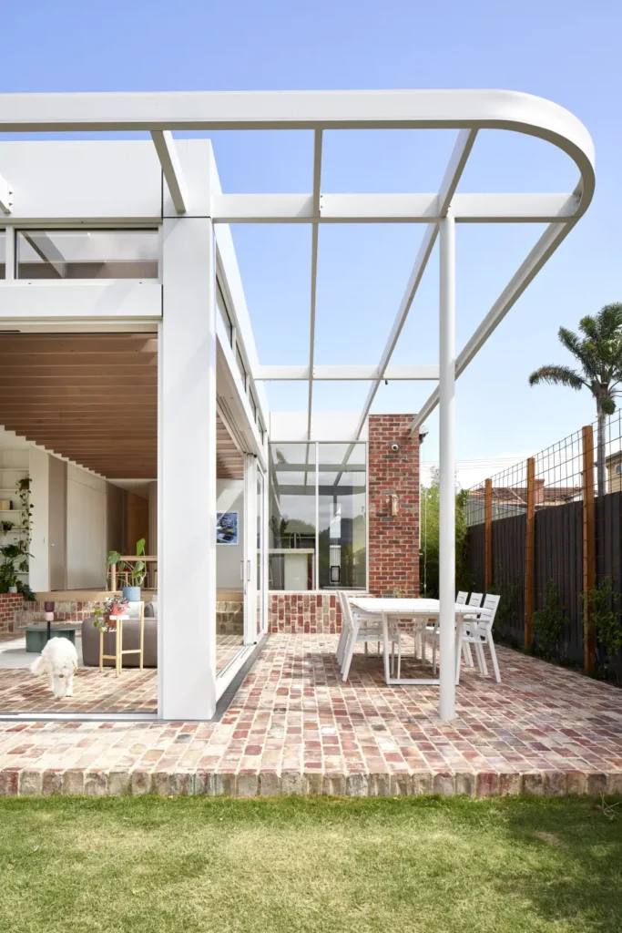 Outdoor terrace of Lindsay house with brick paving, pergola and garden pool in Melbourne