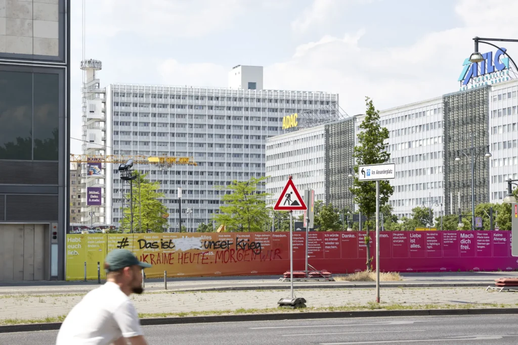 Cyclist passing Pressehaus am Alexanderplatz by GMP Architects in Berlin