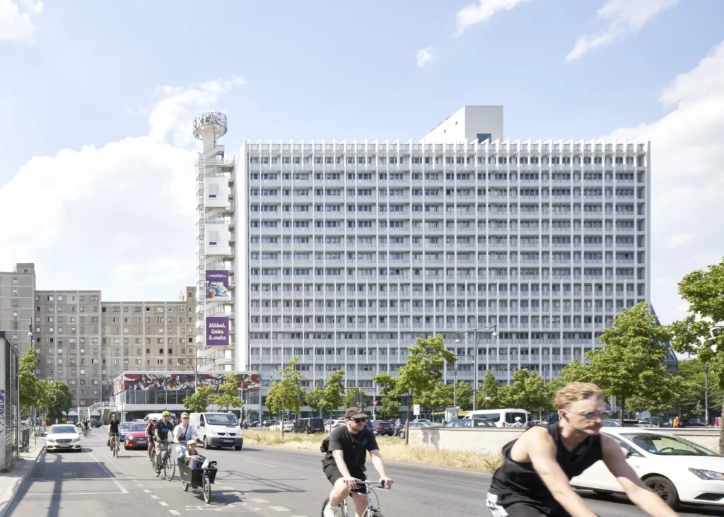 Cyclist passing Pressehaus am Alexanderplatz with green glass facade by GMP Architects