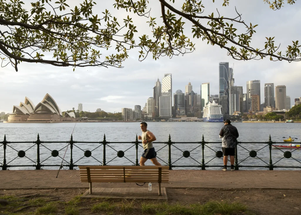 Sydney Opera House with Quay Quarter Tower visible in the CBD skyline behind and pedestrians