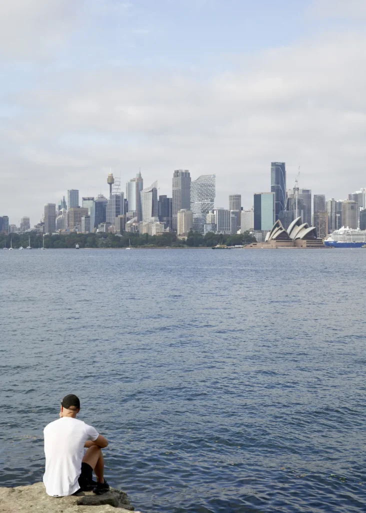 Man looking across to Sydney Operah House and CBD with Quay Quarter tower and cruise ship
